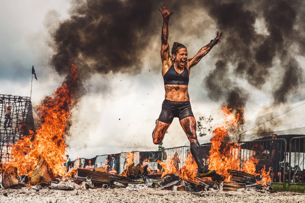 Woman jumping through fire during an obstacle race event